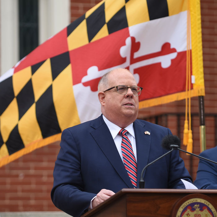 Image of Governor Larry Hogan in front of a Maryland state flag